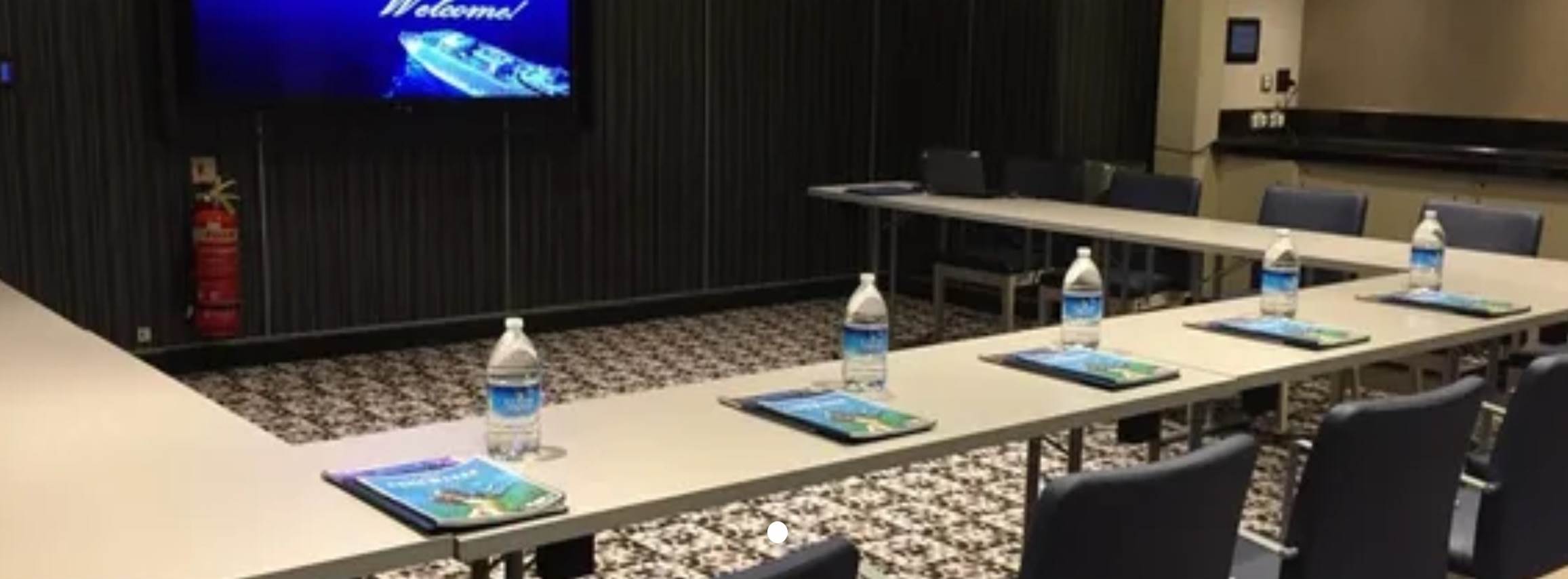 A table with water bottles and a screen

Description automatically generated